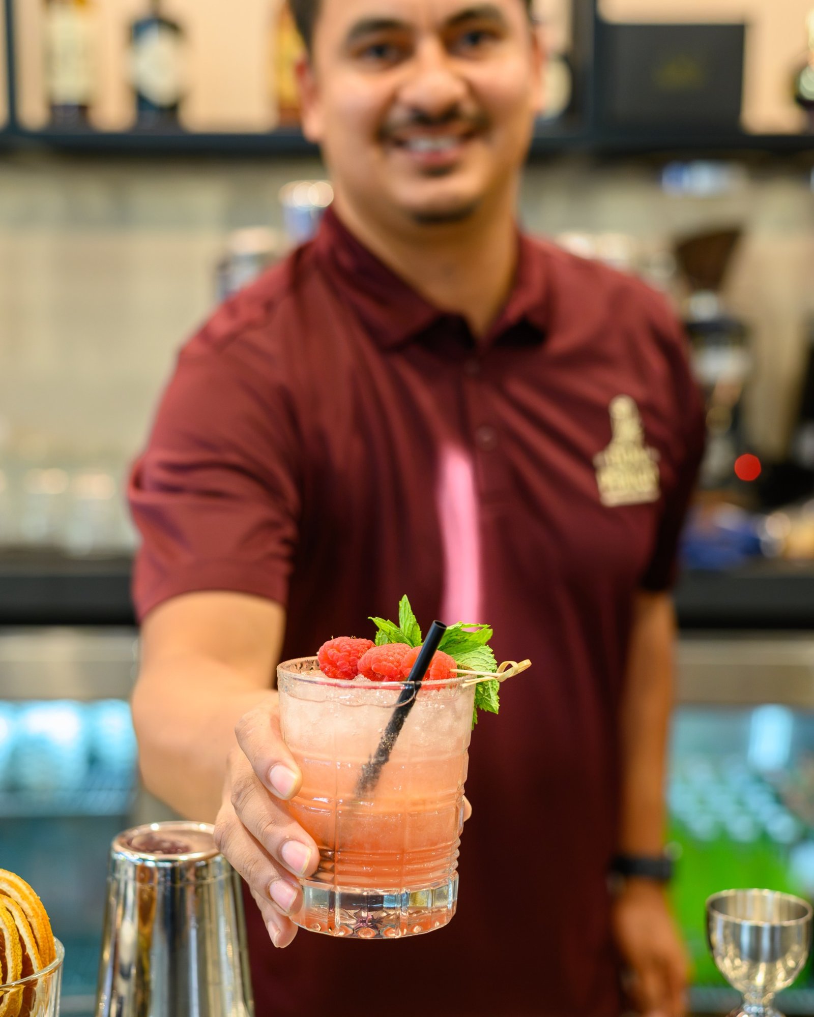 A Don Perico bartender presenting a fresh raspberry cocktail